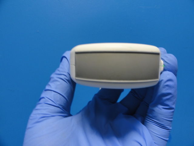a hand in a blue glove holding a small probe head