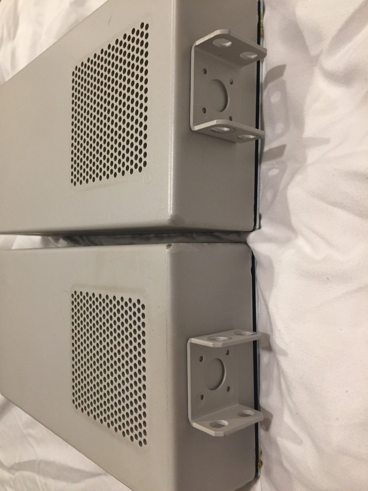 a pair of gray speakers sitting on top of a white sheet