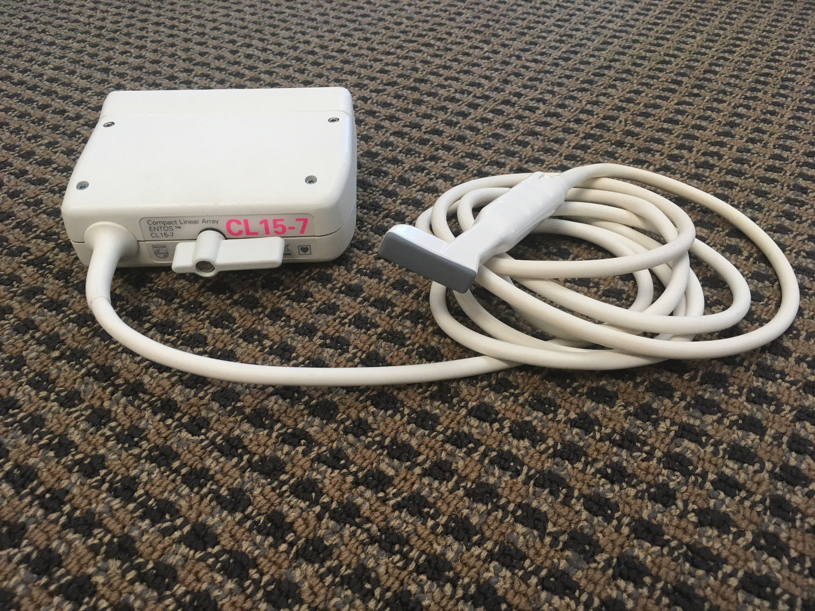 a white box probe sitting on top of a carpet next to a white cord