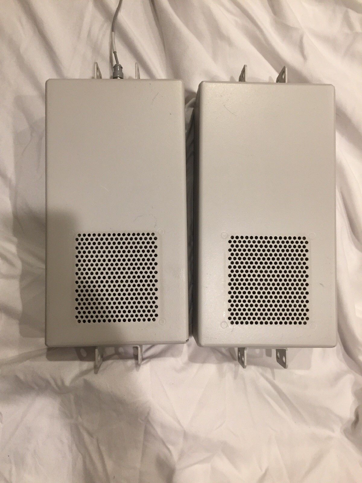 a couple of white speakers sitting on top of a white sheet